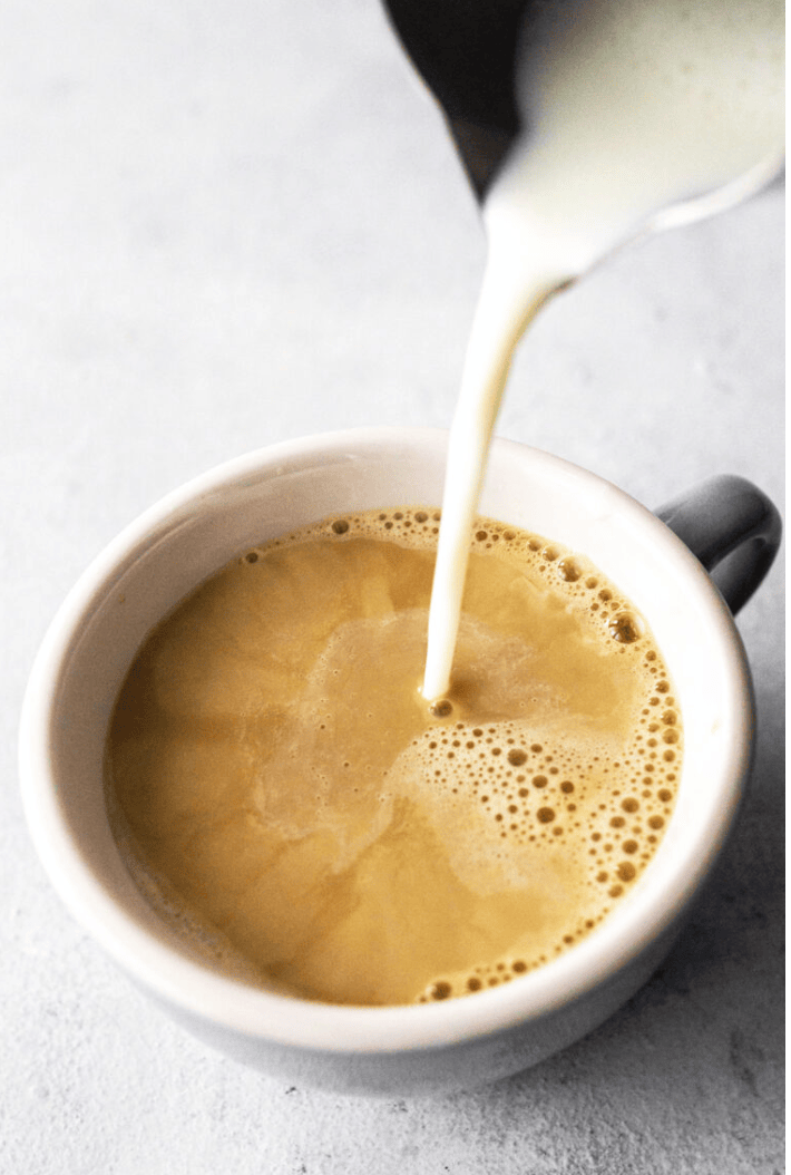 cup of coffee with milk being poured in